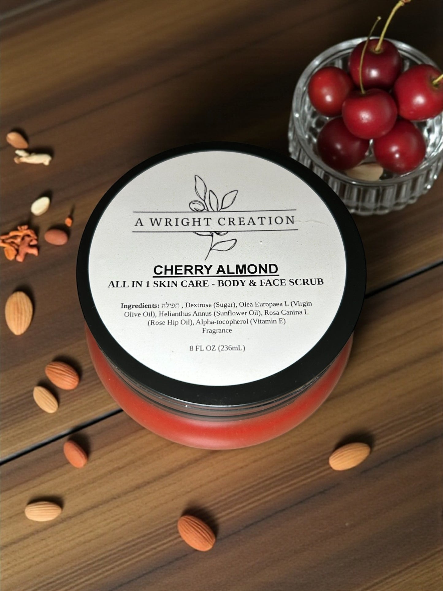 Jar of Cherry Almond skin care scrub with ingredients on a wooden surface