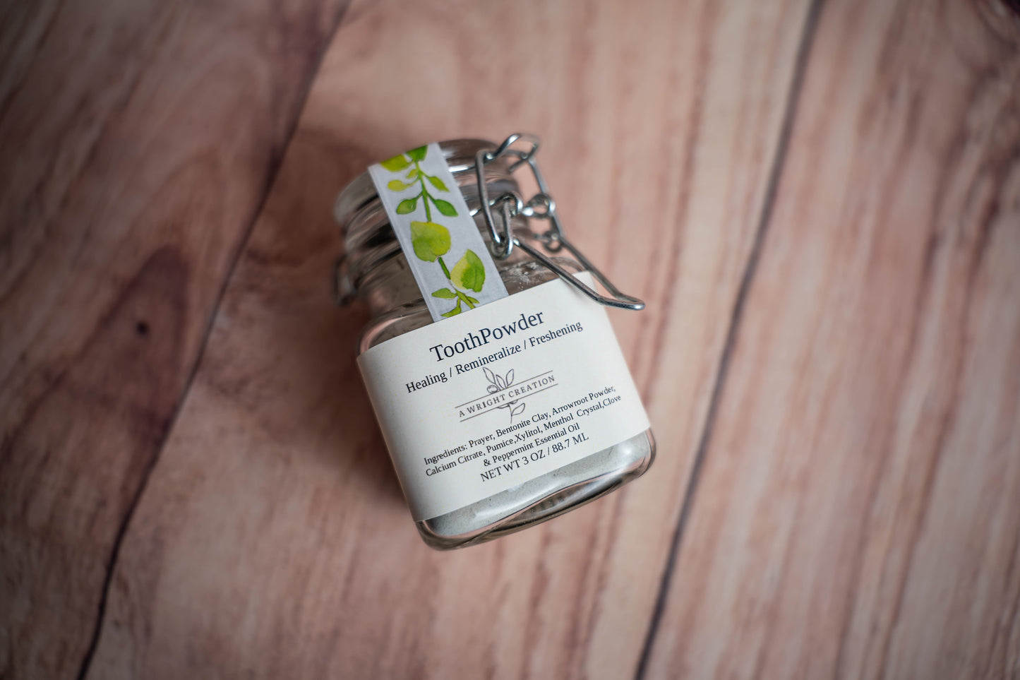 Small glass jar labeled 'Tooth Powder' on a wooden surface