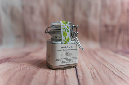 A Wright Creation Healing Tooth Powder in a reusable glass jar with eco-friendly packaging, formulated with bentonite clay, menthol crystals, and natural ingredients to heal, remineralize, and freshen teeth, ideal for sensitive oral care routines.