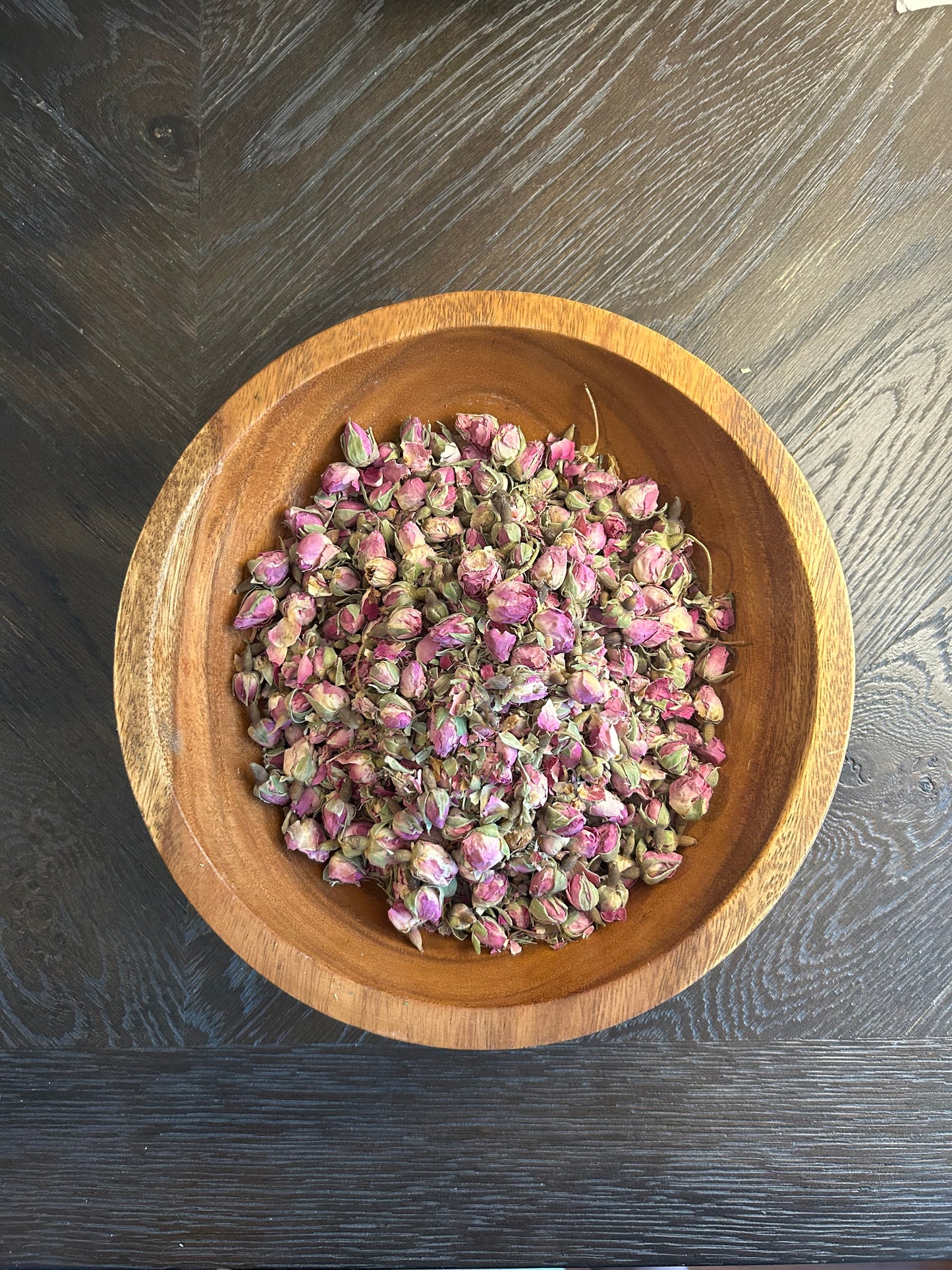 A wooden bowl filled with Wright Way pink Organic Rose Buds.