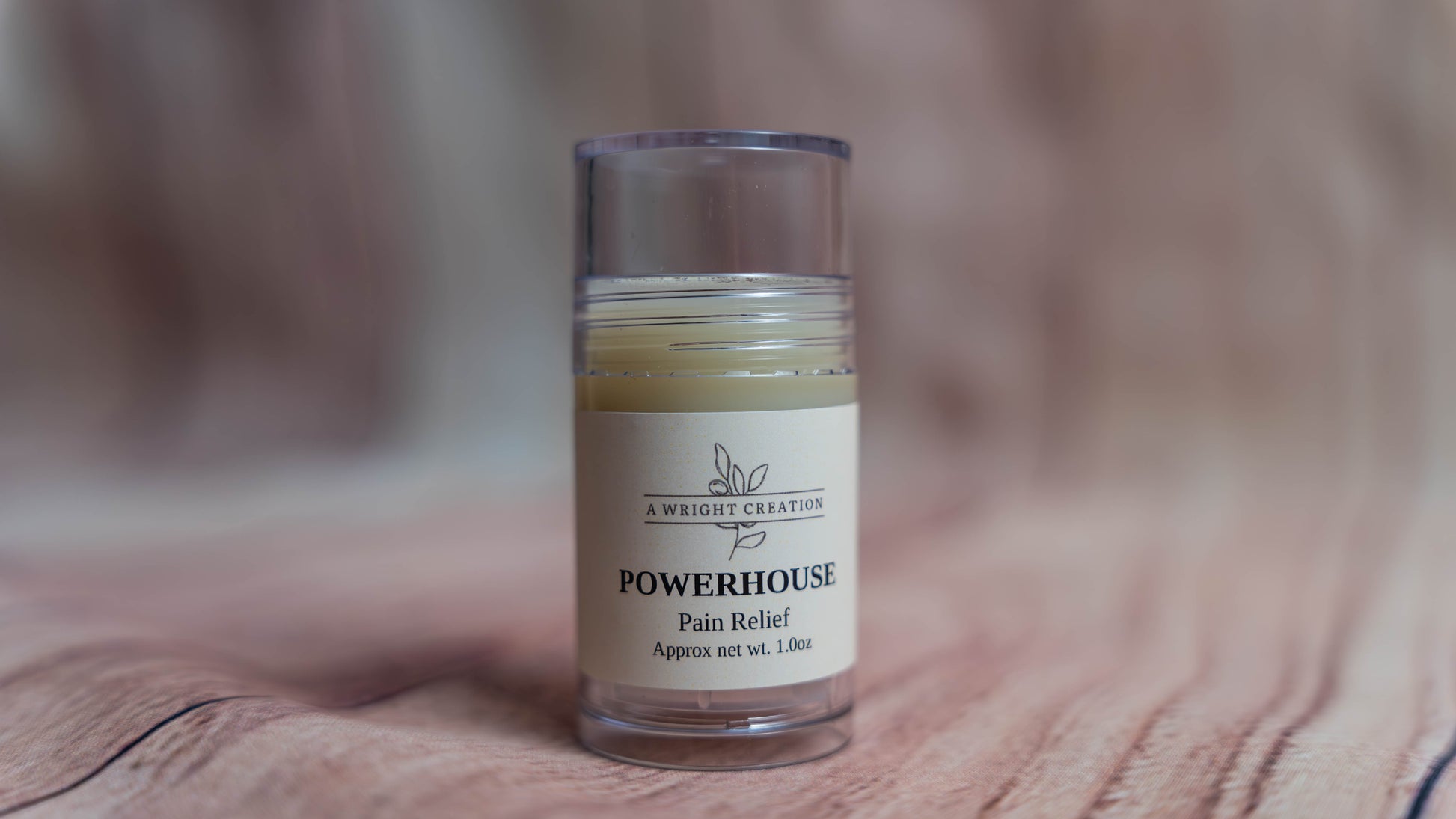 Small glass jar labeled 'Powerhouse Pain Relief' on a wooden surface with a blurred background