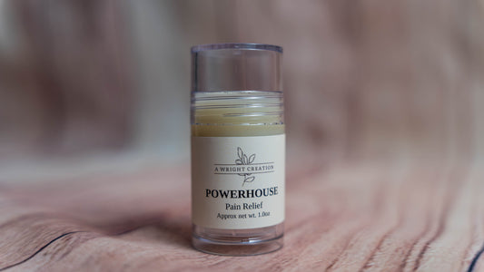 Small glass jar labeled 'Powerhouse Pain Relief' on a wooden surface with a blurred background