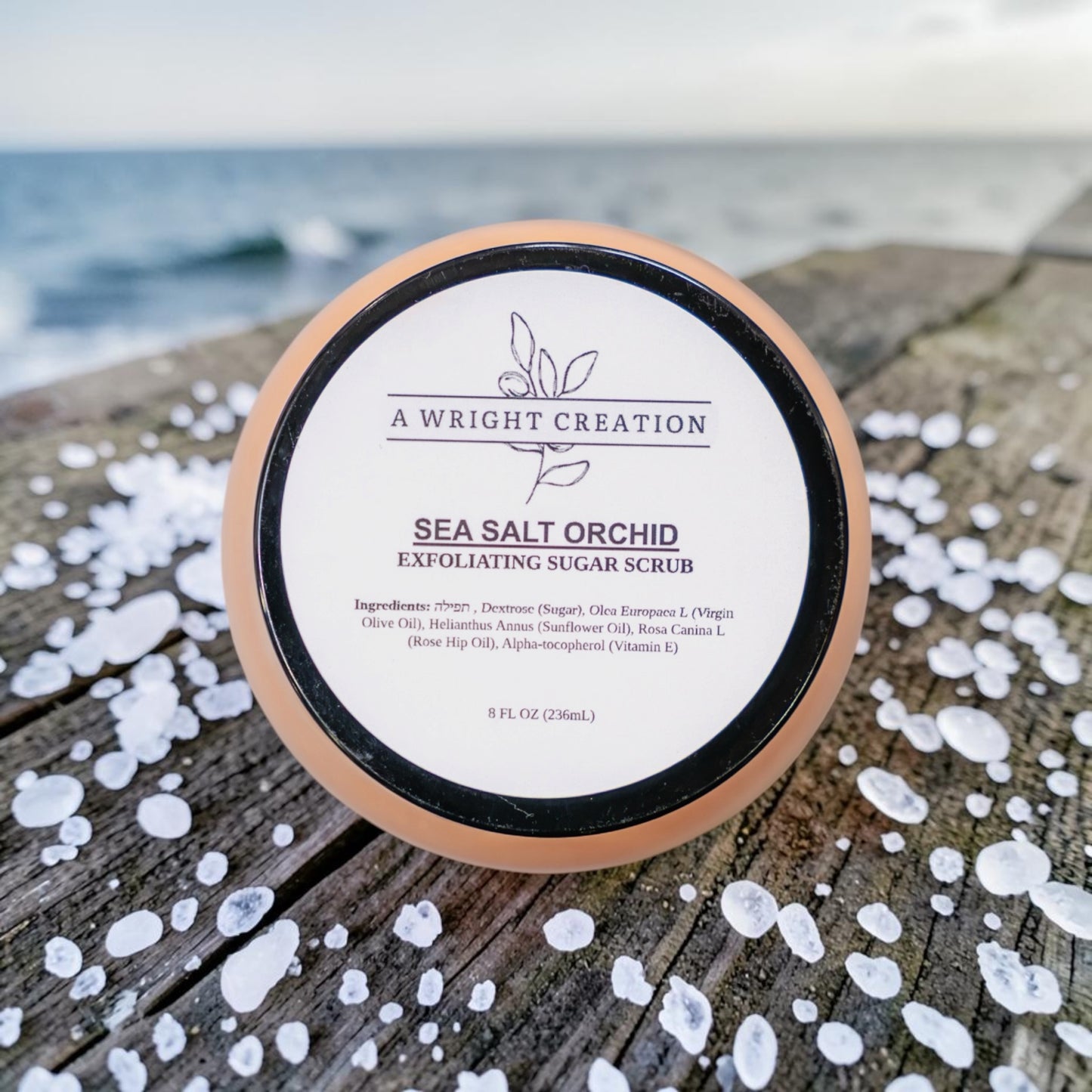 Jar of 'A Wright Creation' Sea Salt Orchid Exfoliating Sugar Scrub on a wooden surface with sea salt crystals.