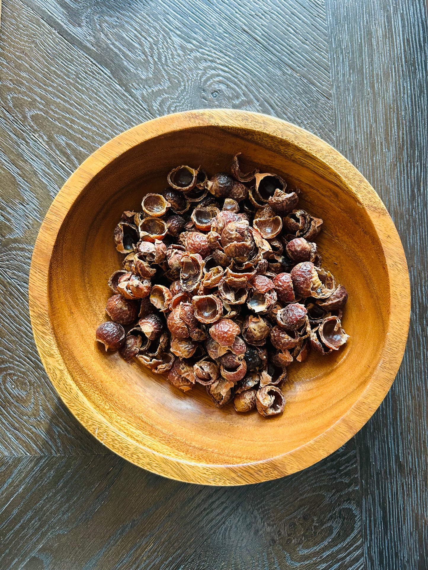 Wooden bowl filled with Deseeded Soap Nuts Deseeded on a wooden surface