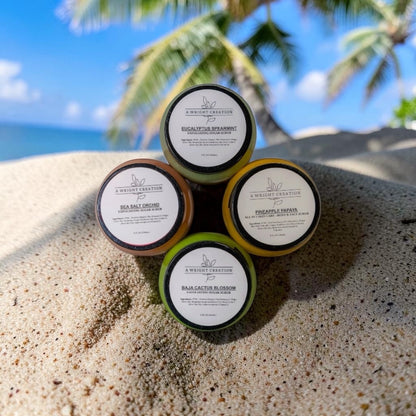 Five small containers with labels on a sandy surface with a tropical background